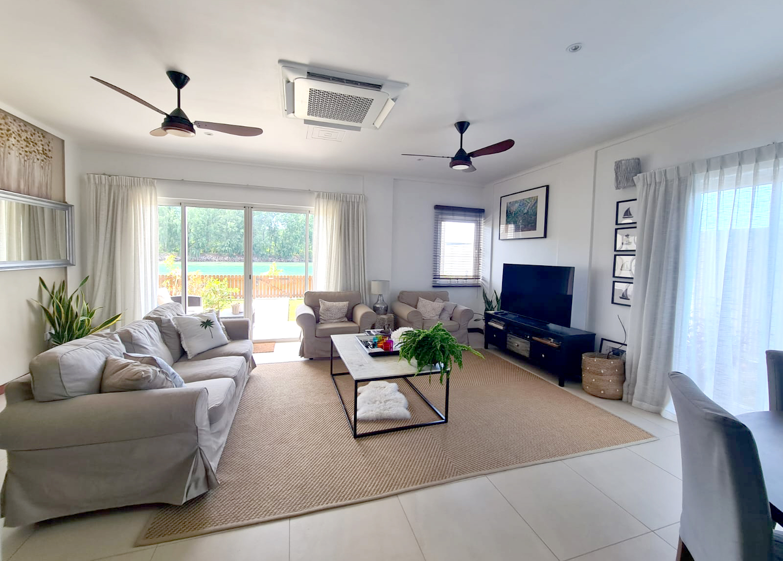 Bright sitting room with cream sofas and a view of the sea through the garden doors