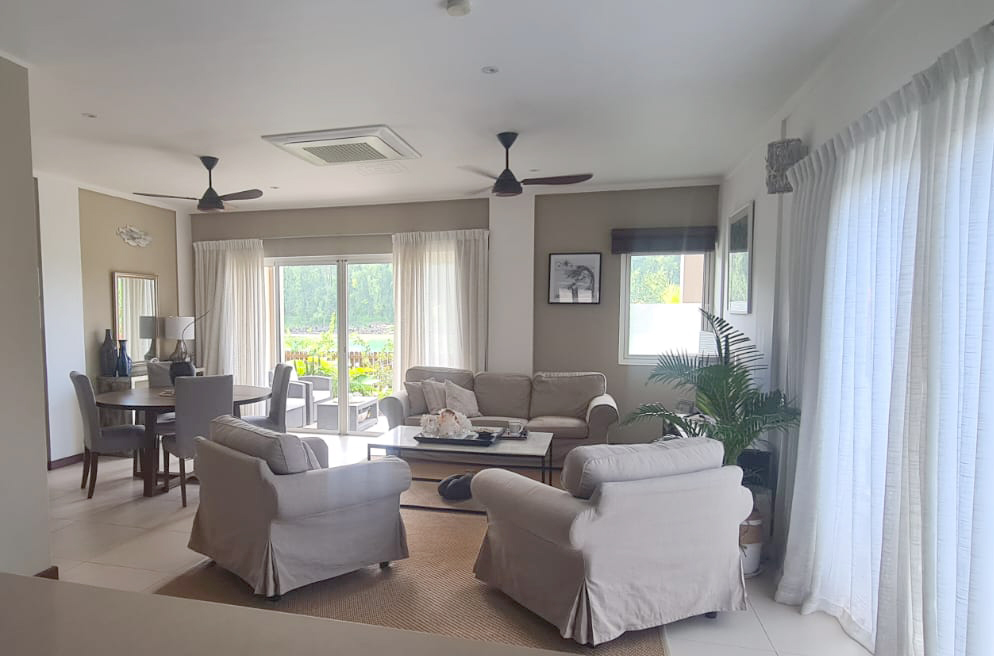 Living and dining space seen from the kitchen, with the verandah and sea beyond
